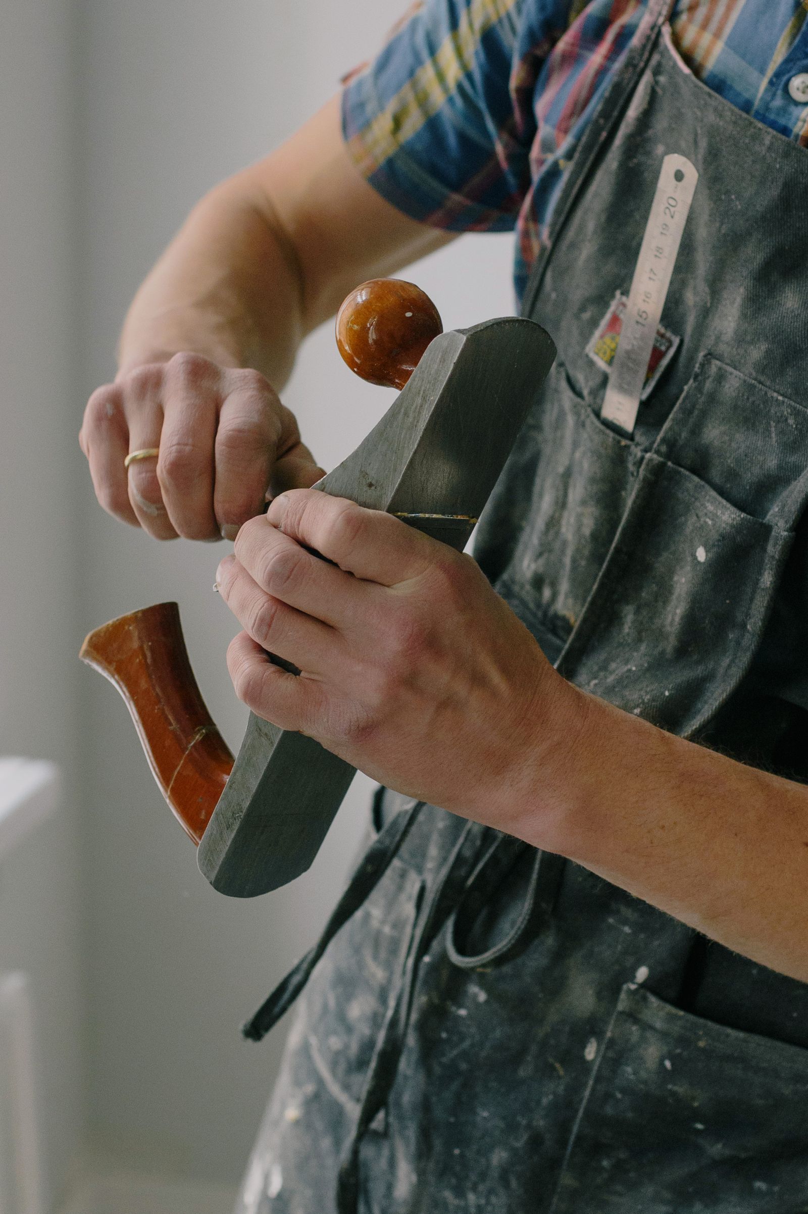 Handwerker mit Lederschürze hält einen Holzhobel in den Händen