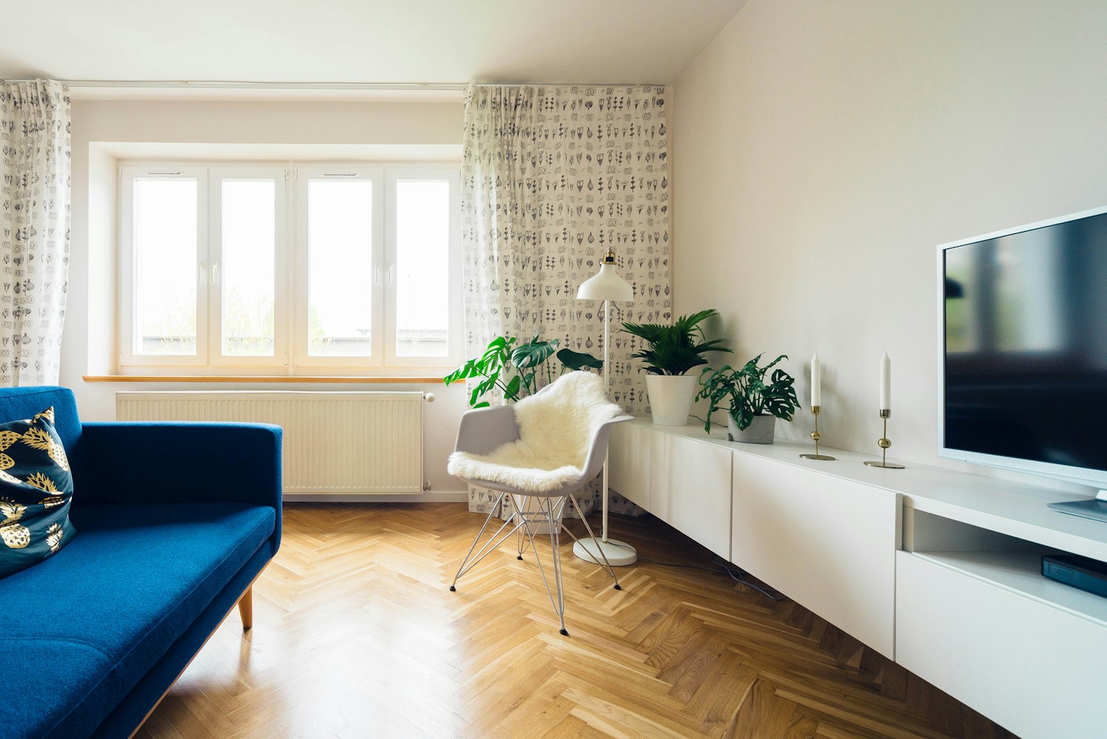 Wohnzimmer mit blauem Sofa auf klassischem Eichen-Fischgrätparkett